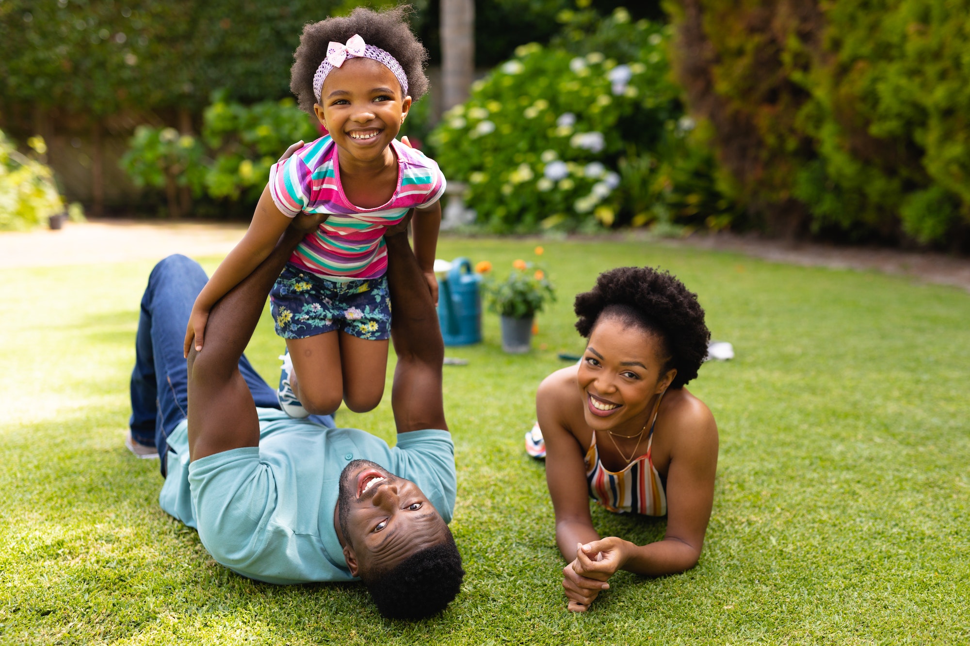 Portrait of smiling african american family lying on grass at backyard garden